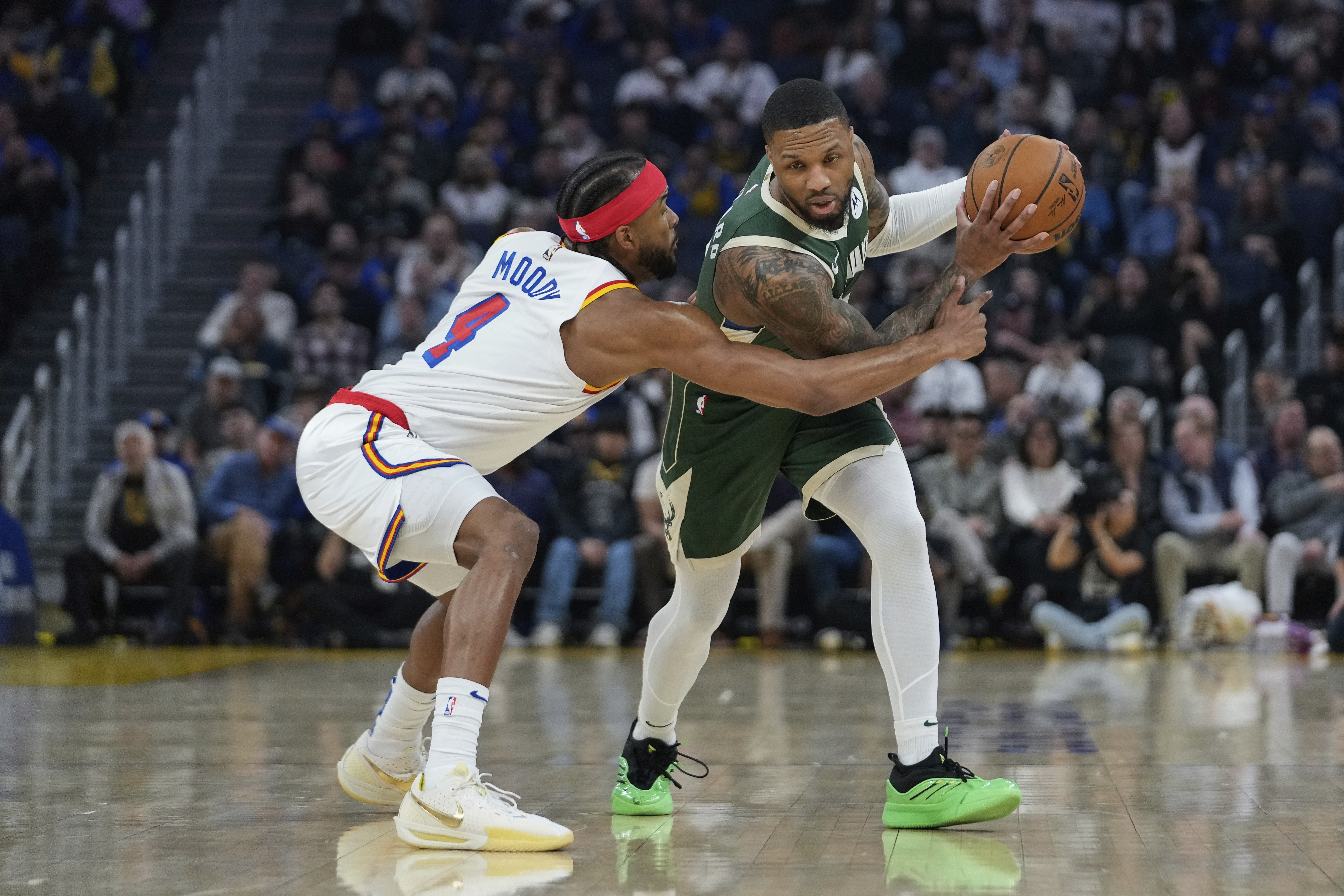 Golden State Warriors guard Moses Moody, left, tries to knock the ball away from Milwaukee Bucks guard Damian Lillard during the first half of an NBA basketball game Tuesday, March 18, 2025, in San Francisco.