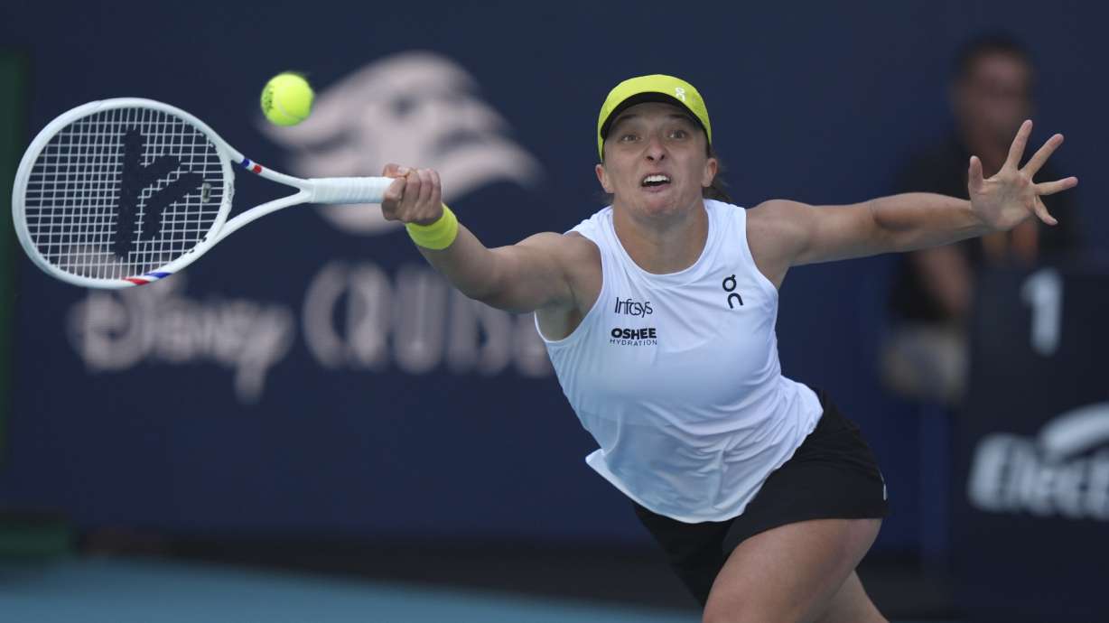 Iga Swiatek, of Poland, hits a return to Caroline Garcia, of France, during the Miami Open tennis tournament, Friday, March 21, 2025, in Miami Gardens, Fla.