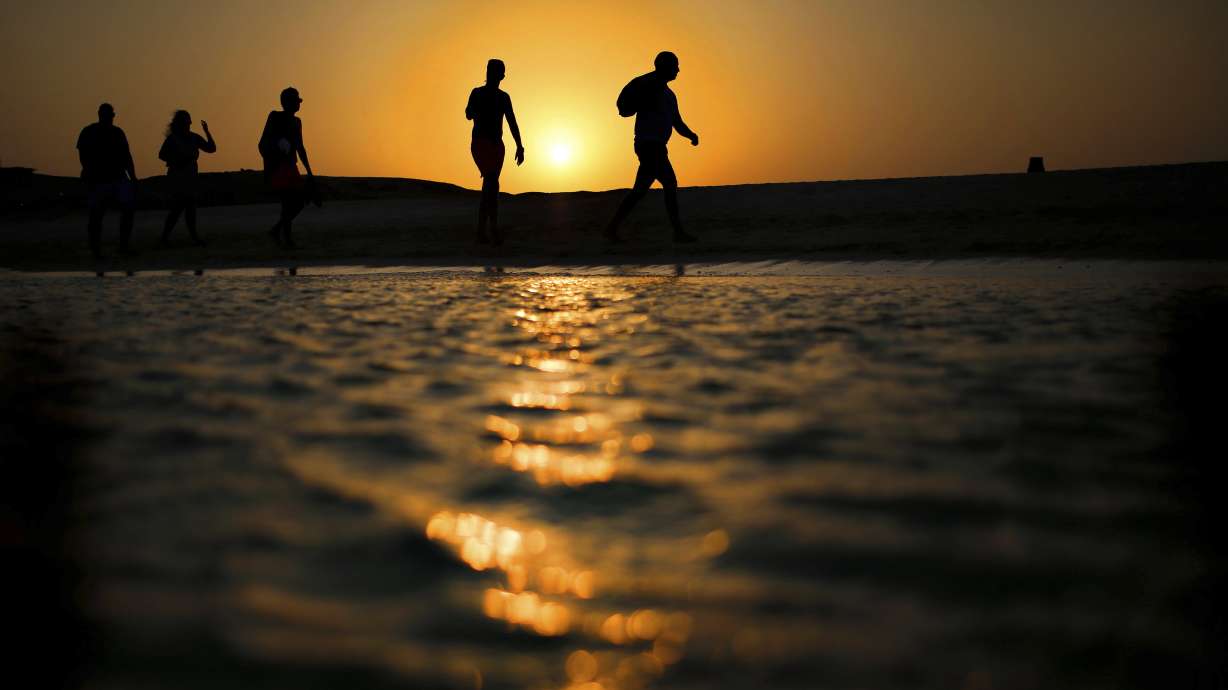 Tourists walk on the Giftun Island beach as the sun sets over the Red Sea in Hurghada, Egypt, Aug. 20. A tourist submarine sank off the Egyptian resort town of Hurghada, leaving six people dead and others injured on Thursday.
