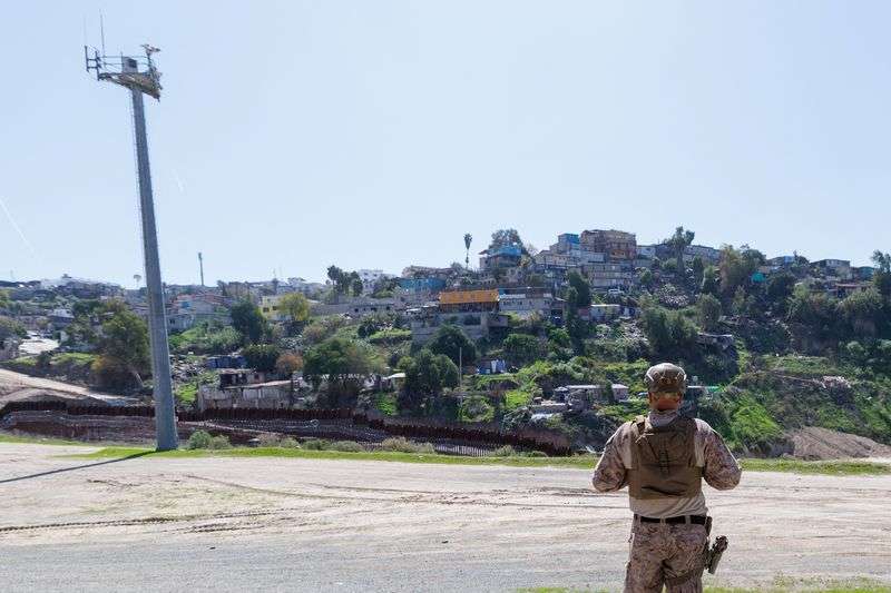 A member of the U.S. Military stands near electronic monitoring equipment between the primary and secondary border walls with Tijuana, Mexico, and the United States in San Diego, Calif., Tuesday.