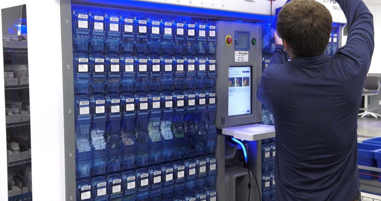 An Intermountain Health employee filling a machine that fills prescriptions at the center.