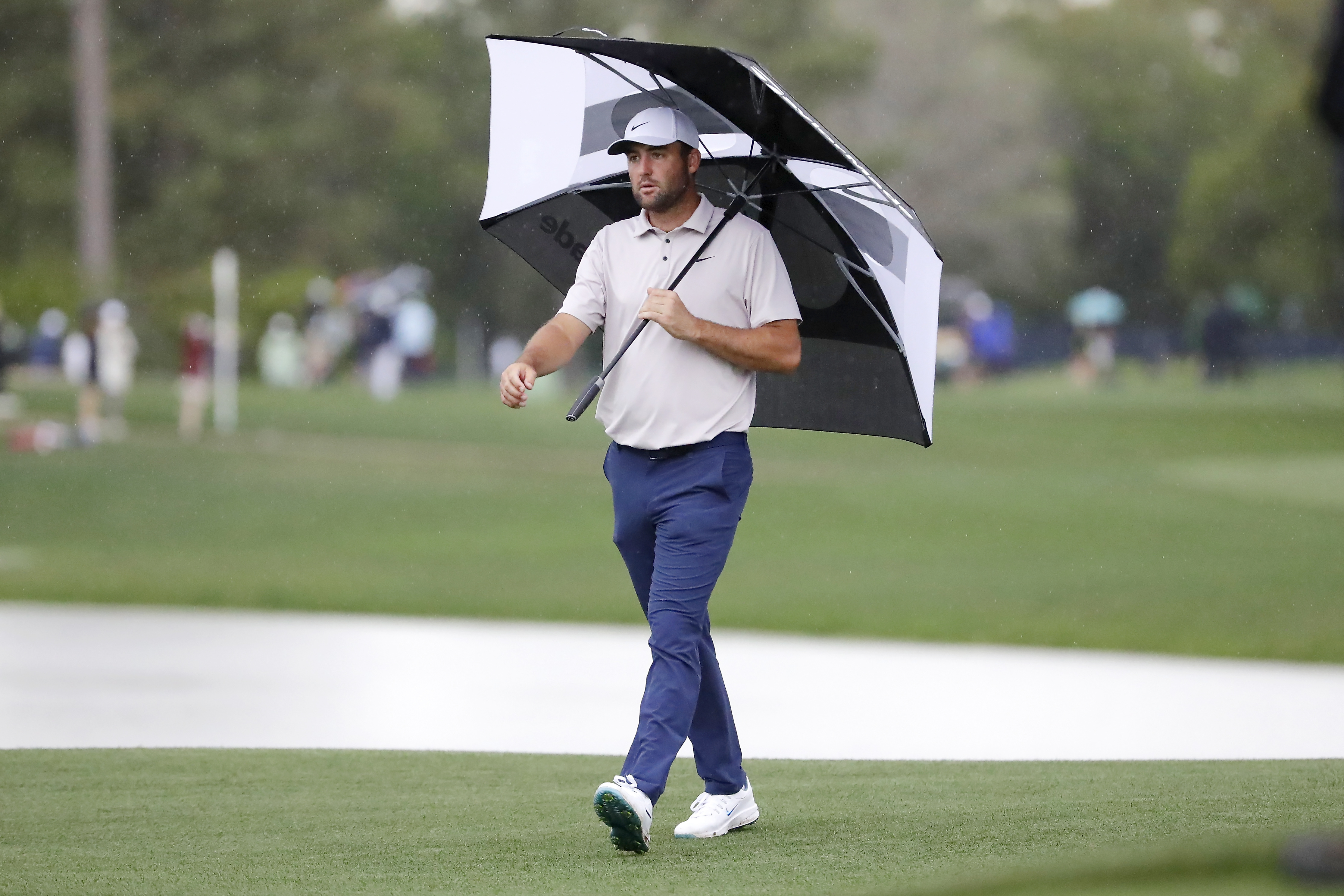 Scottie Scheffler walks onto the 17th green under an umbrella in the rain during the first round of the Houston Open golf tournament, Thursday, March 27, 2025, in Houston.