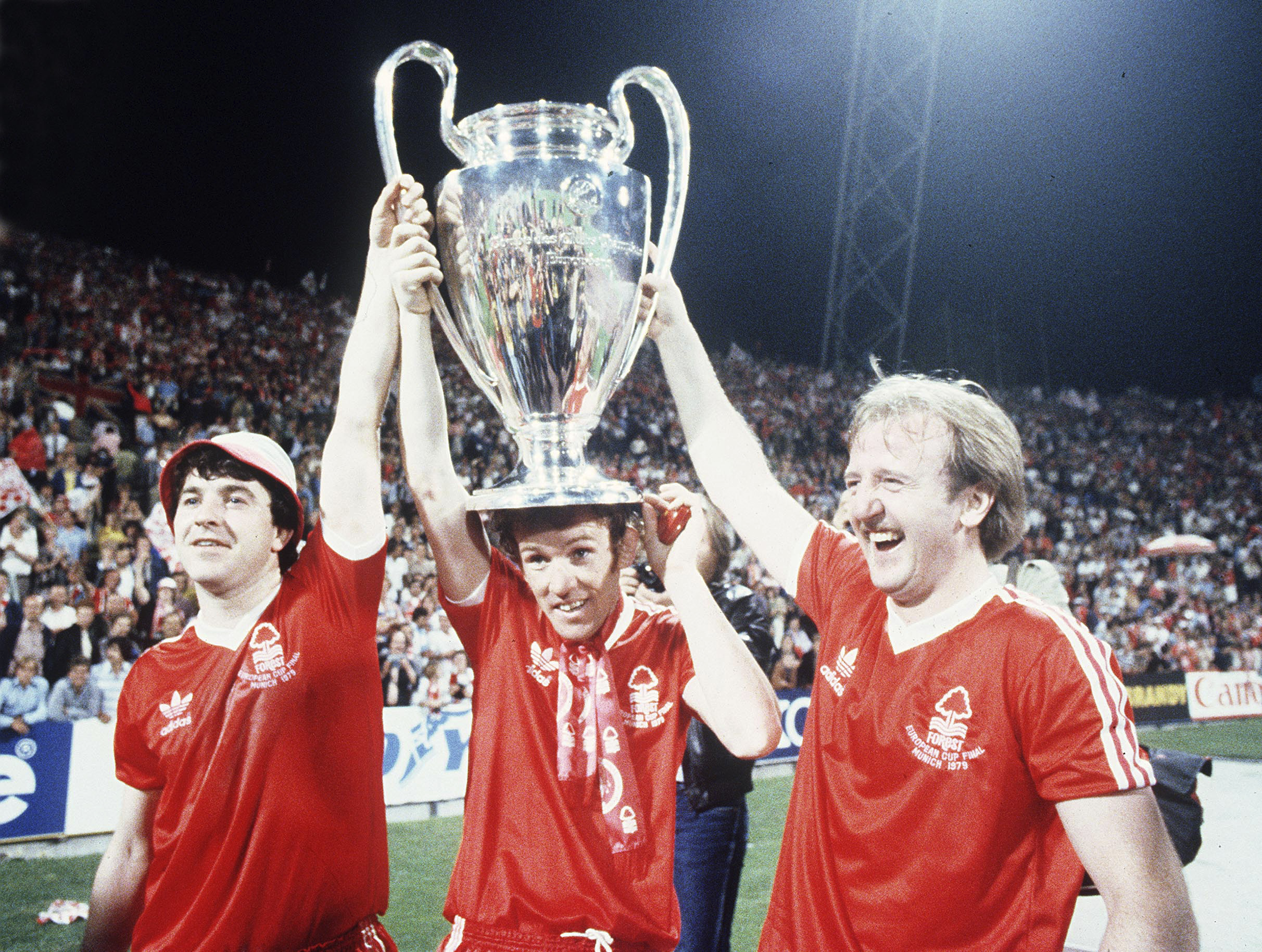 FILE - Nottingham Forest's John Robertson, left, Ian Bowyer, center, and Kenny Burns, right, carry the European Cup in triumph after their 1-0 win against Malmo FF in Munich, Germany, May 30, 1979.