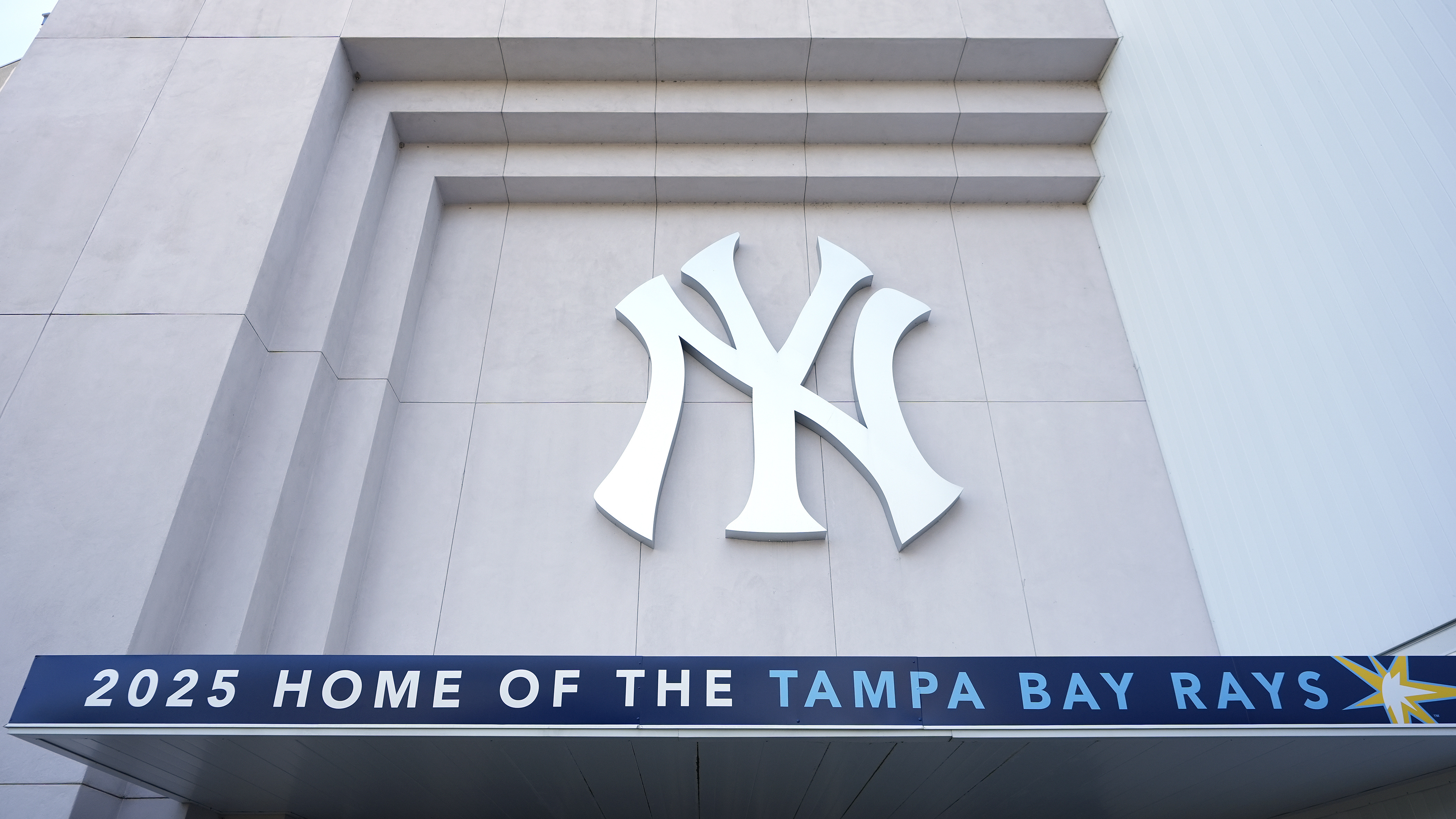 A Tampa Bay Rays banner hangs near a New York Yankees logo outside George M. Steinbrenner Field during a stadium tour Wednesday, March 26, 2025, in Tampa, Fla.