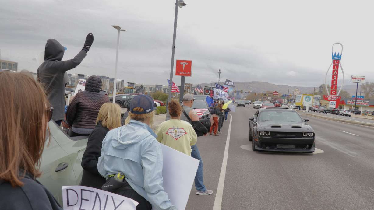Protesters wave signs outside a Tesla dealership in South Salt Lake during a demonstration on Saturday. It was part of a global "Tesla Takedown" taking place at many company locations.