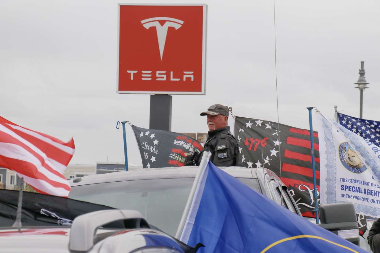 A member of the Utah Patriots stands in his truck outside a Tesla dealership in South Salt Lake during a demonstration on Saturday. It was part of a global "Tesla Takedown" taking place at many company locations.