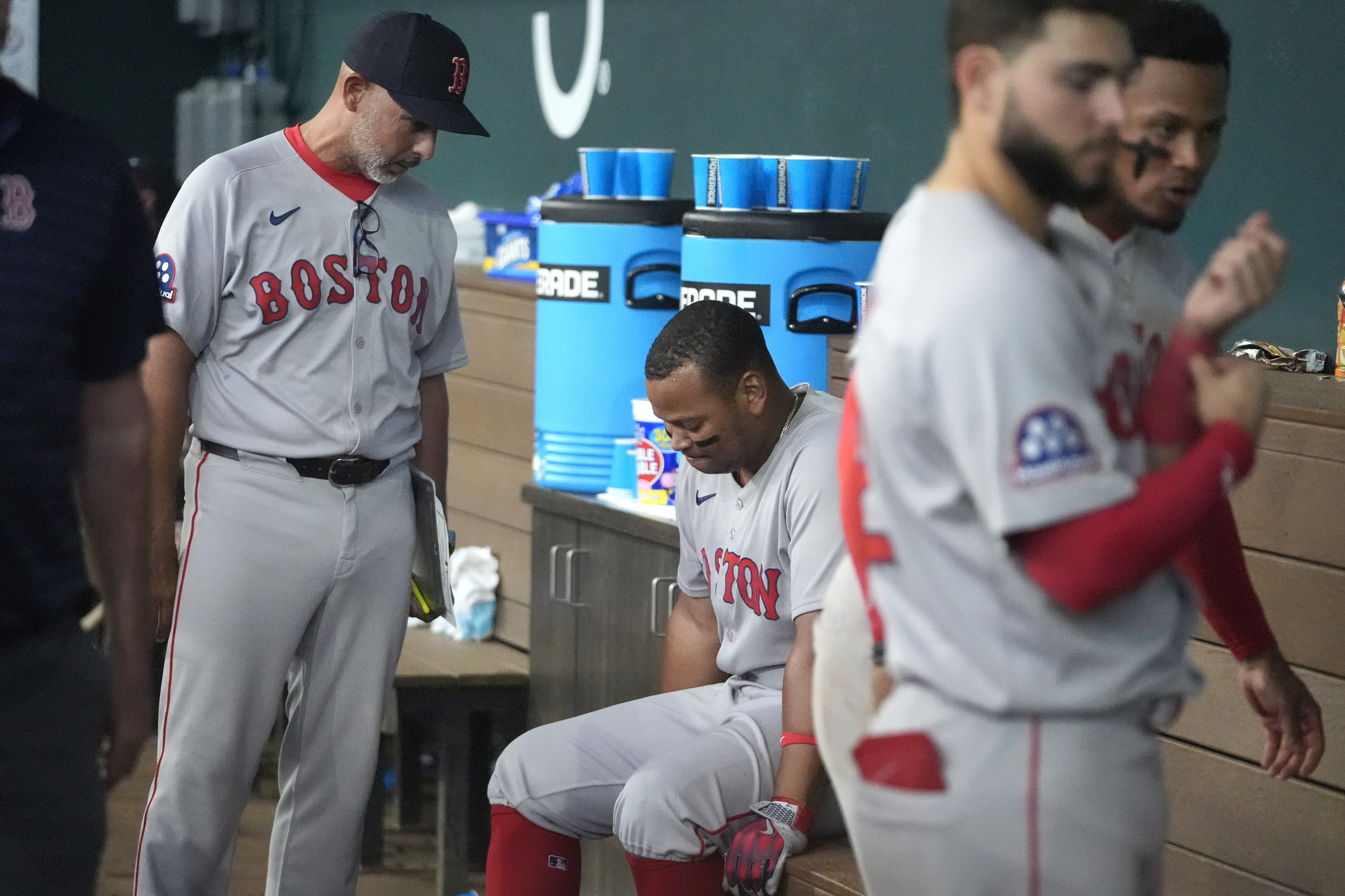 Boston Red Sox manager Alex Cora, left, talks to Rafael Devers, center, in the dugout after a baseball game against the Texas Rangers, Sunday, March 30, 2025, in Arlington, Texas.