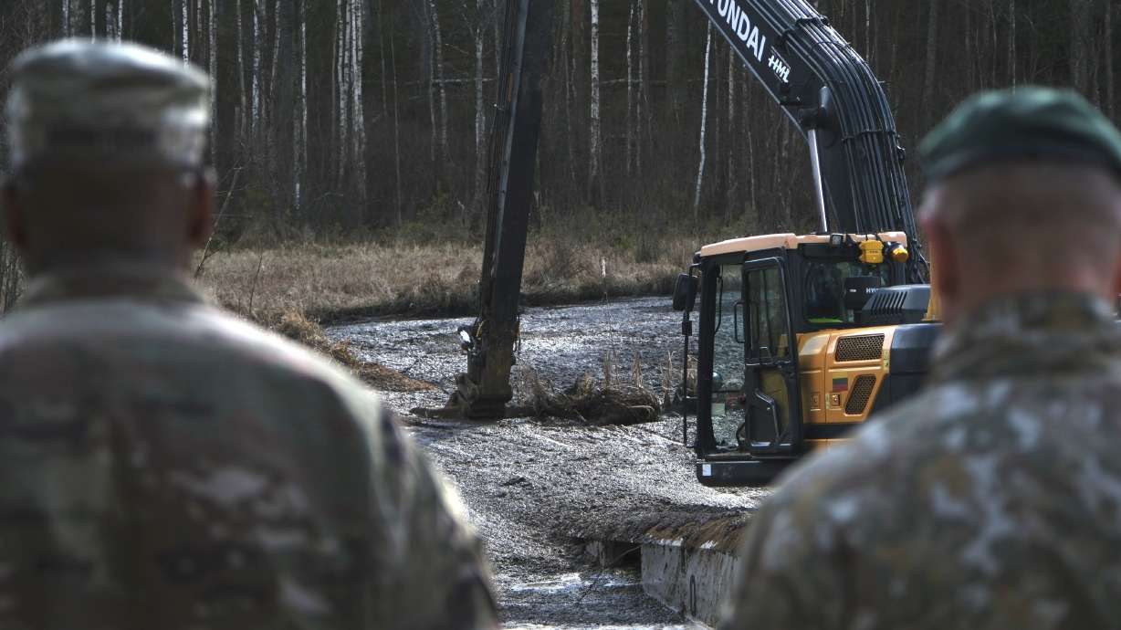 U.S. Army soldiers and Lithuanian Army and emergency services personnel discuss their plan to recover four U.S. soldiers in a U.S. Army M88 Hercules underwater in a swamp near a training area near Pabadre, Lithuania, Thursday, March 27.