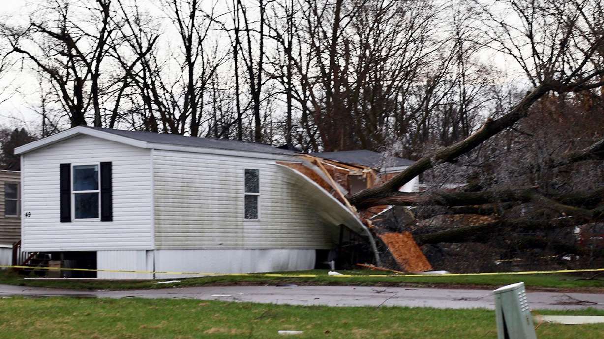 A large tree rests on top of a mobile home after a storm Sunday, in Kalamazoo, Mich.
