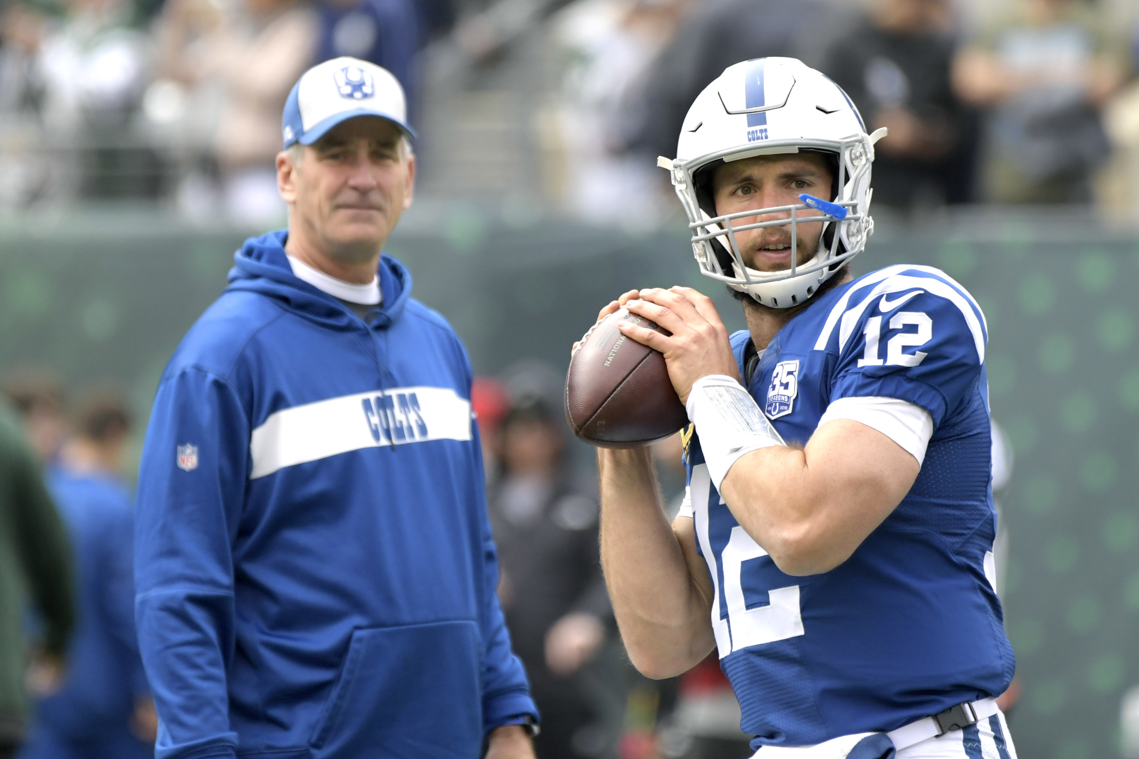 FILE - Indianapolis Colts quarterback Andrew Luck (12) warms up as head coach Frank Reich looks on prior to an NFL football game against the New York Jets, in East Rutherford, N.J, Oct. 14, 2018.
