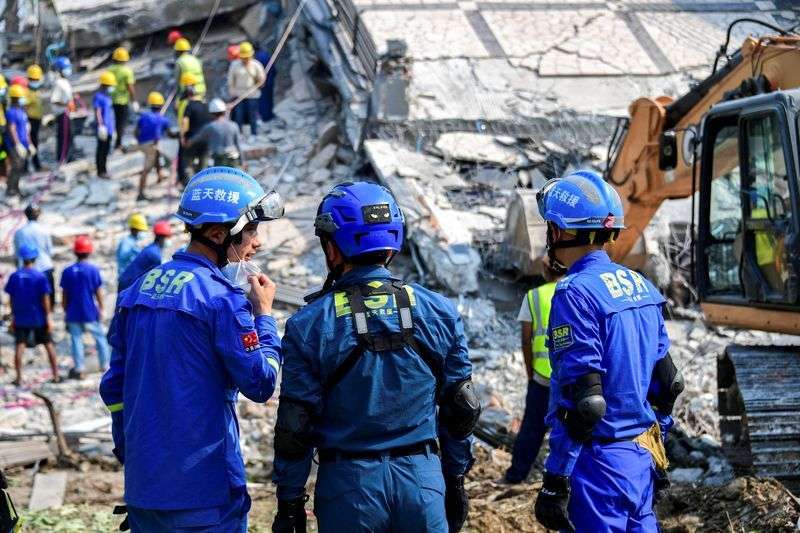 Chinese rescue workers stand at the site of a collapsed building, in the aftermath of a strong earthquake, in Mandalay, Myanmar, Monday.