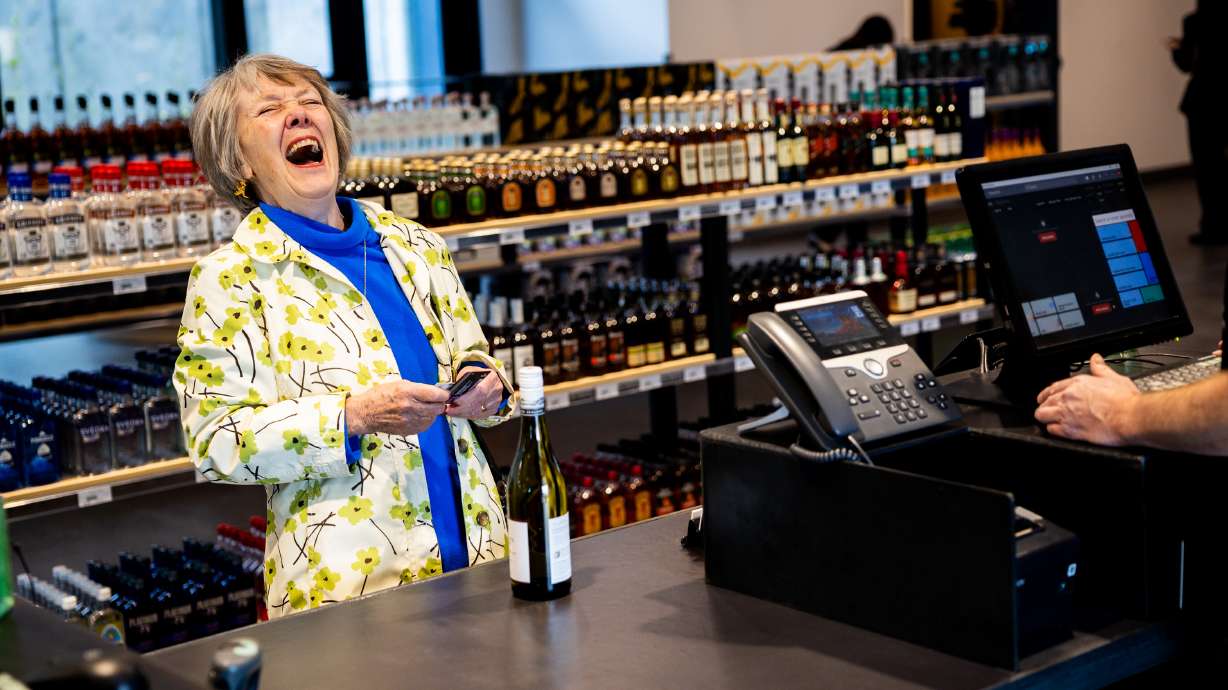 Joan Ogden laughs as she checks out as the first customer at the new liquor store at 1615 S. Foothill Dr. in Salt Lake City on Monday.