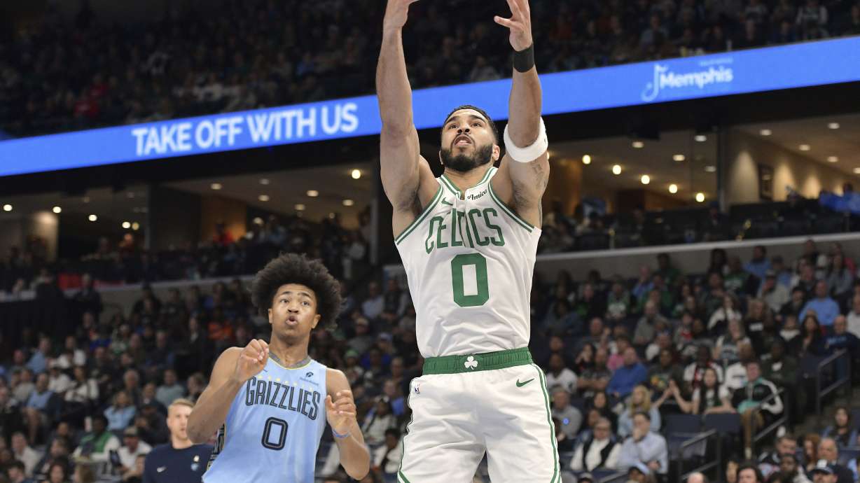 Boston Celtics forward Jayson Tatum, right, reaches for the ball ahead of Memphis Grizzlies forward Jaylen Wells, left, in the first half of an NBA basketball game Monday, March 31, 2025, in Memphis, Tenn.
