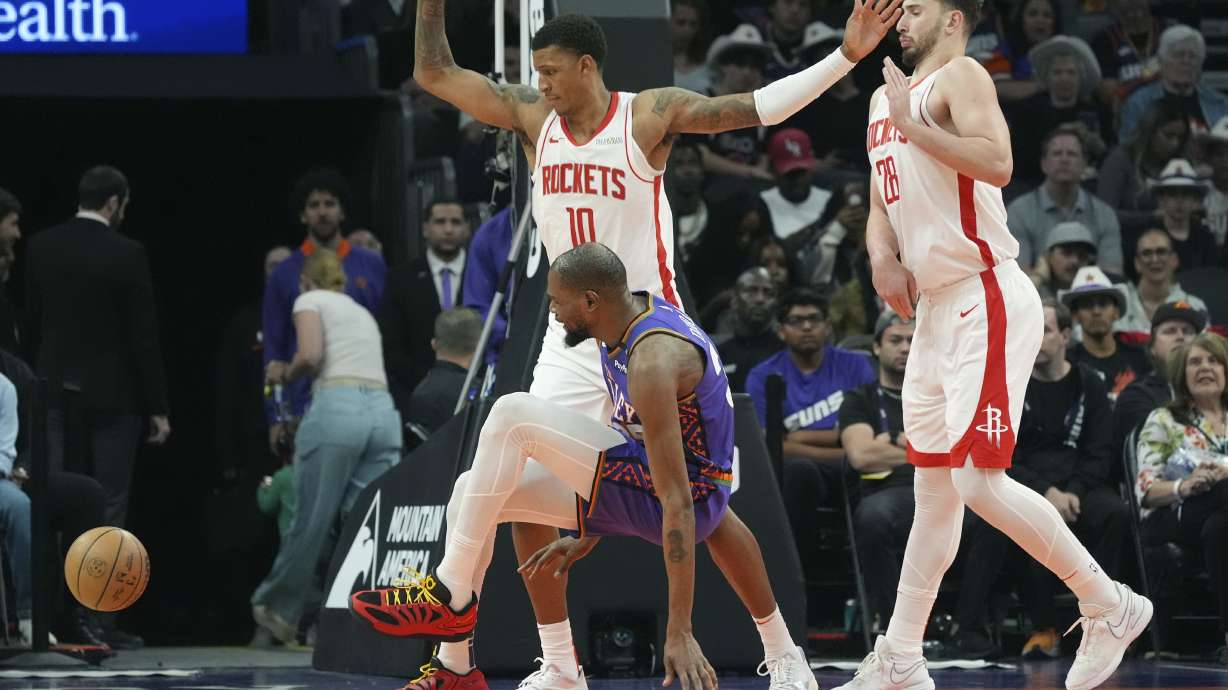 Phoenix Suns forward Kevin Durant, center, sprains an ankle as the drives to the basket against Houston Rockets forward Jabari Smith Jr. (10) and Rockets center Alperen Sengun (28) during the second half of an NBA basketball game Sunday, March 30, 2025, in Phoenix.