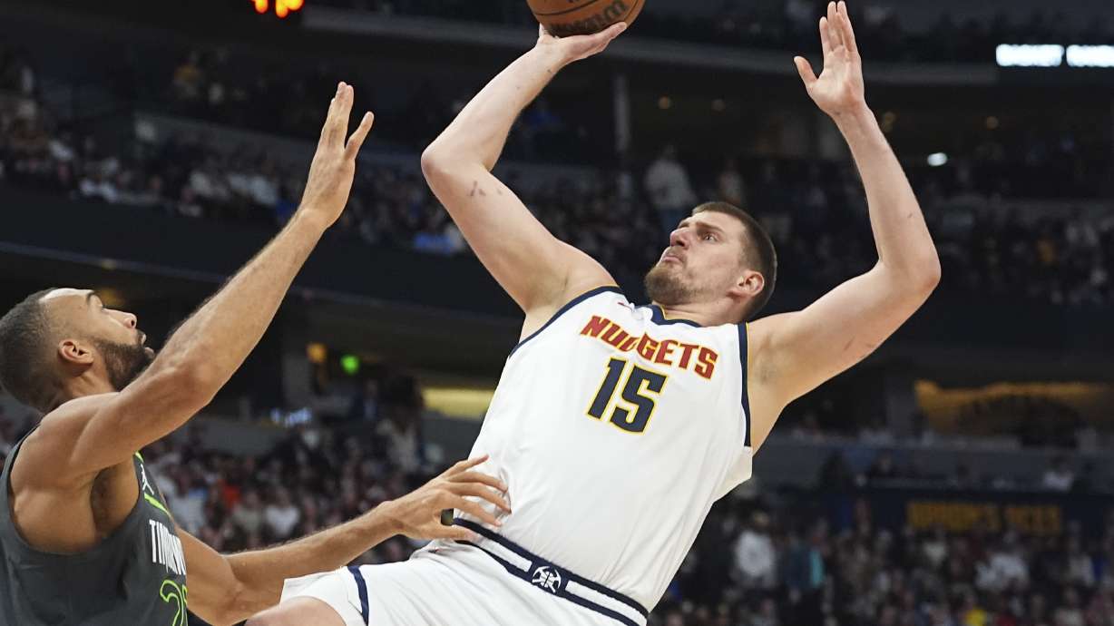 Denver Nuggets center Nikola Jokic, right, shoots for a basket over Minnesota Timberwolves center Rudy Gobert in the first half of an NBA basketball game Tuesday, April 1, 2025, in Denver.
