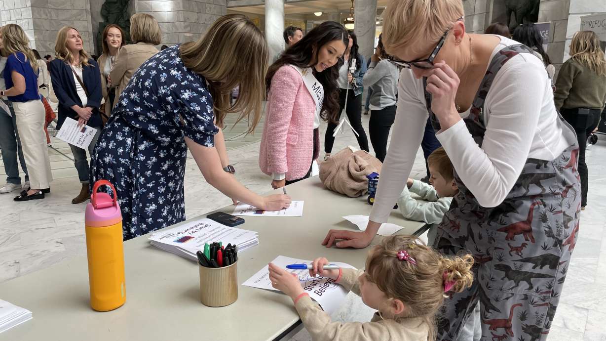 Utah residents, including a mother and her children, sign pledges to Start by Believing victims of sexual abuse at the state capitol on Wednesday.
