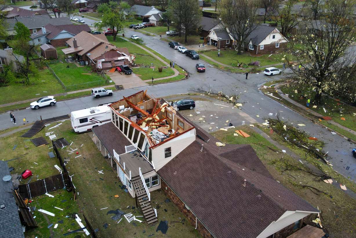 An early morning severe storm damaged homes, destroying the roofs and knocked down power lines, trees, and fences off 96th Street North near Garnett Road, Wednesday, in Owasso, Okla.