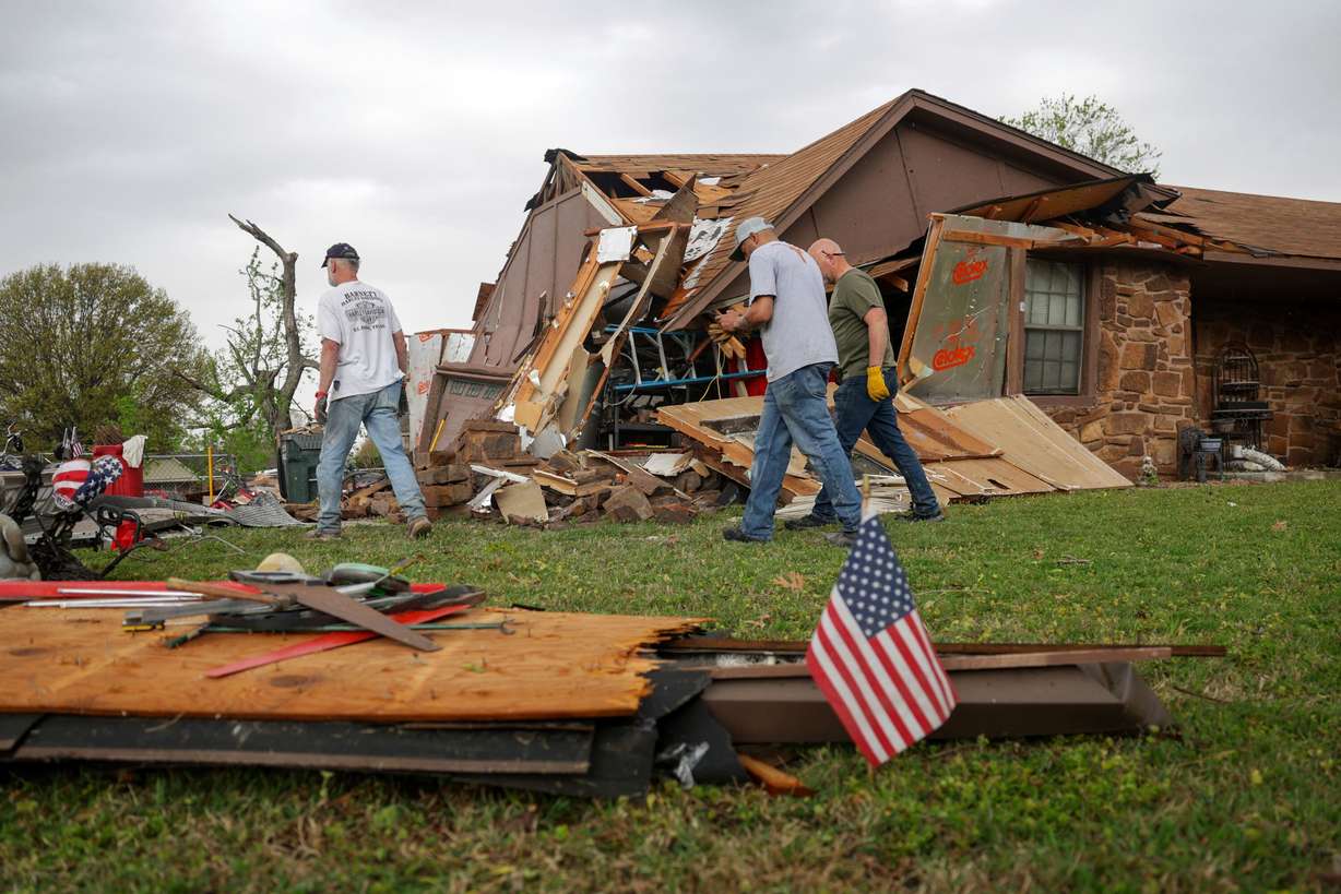 Gary Deripaska, left, cleans up storm damage at his home off 96th Street North just west of Garnett Road, Wednesday, in Owasso, Okla.