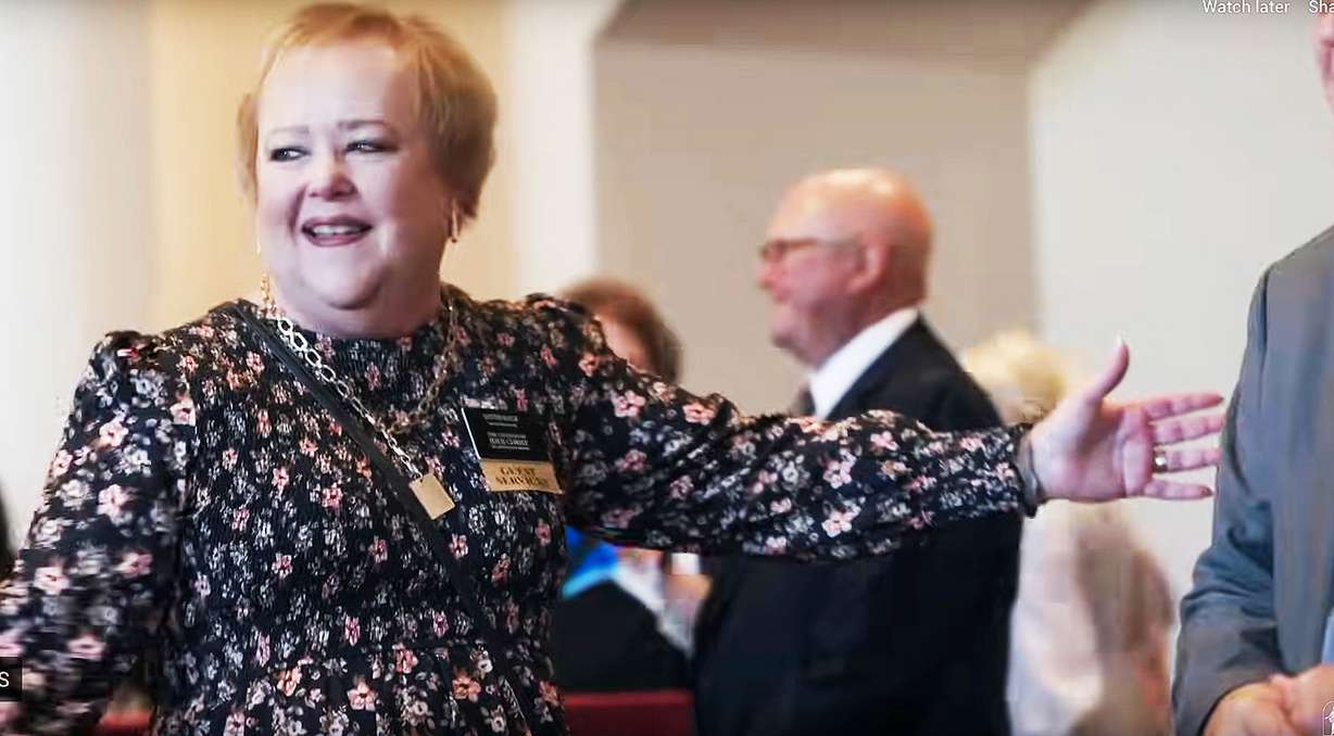 A senior missionary for The Church of Jesus Christ of Latter-day Saints serving with guest services helps seat patrons in the Conference Center in Salt Lake City. Photo is a screenshot from a Behind the Scenes of General Conference video.