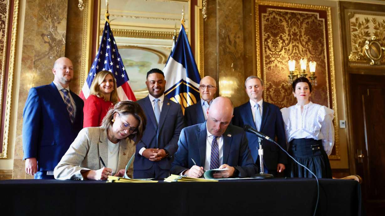 Utah Lt. Gov. Deidre M. Henderson and Gov. Spencer Cox sign a ceremonial bill during a press conference to address online safety, student focus and digital choice held in the gold room at the Capitol in Salt Lake City on Friday.