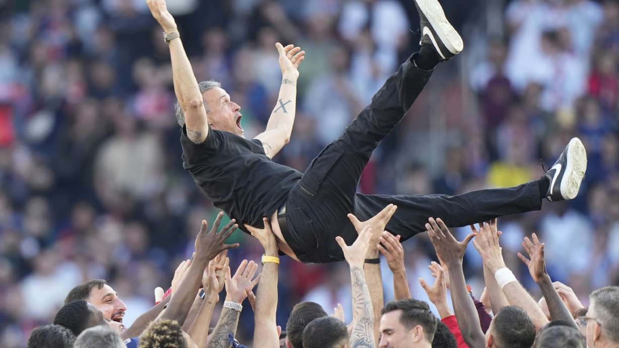 Paris Saint-Germain players throw PSG's head coach Luis Enrique in the air after they won the French League One soccer match between Paris Saint-Germain and Angers at Parc des Princes stadium in Paris, Saturday, April 5, 2025.