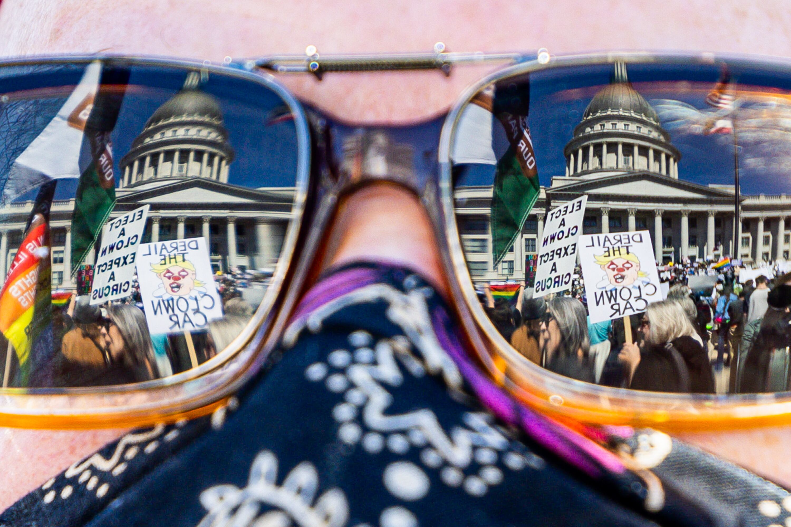 Utahns protesting during a National Day of Protest against President Donald Trump and Elon Musk can be seen through the reflection of Dustin Hendel’s sunglasses at the Capitol in Salt Lake City on Saturday.