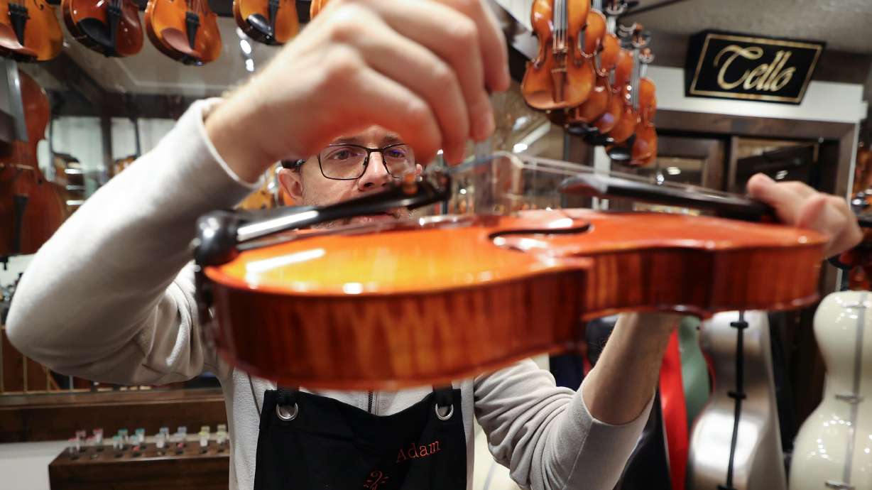 Adam Day, Day Violins owner, inspects a customer’s violin brought in for repairs at Day Violins in Murray on March 20.