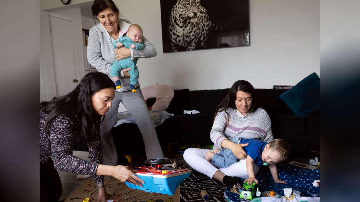 Children’s Service Society of Utah parent educator Kat Lora, left, arranges toys for Theo Williams Caro, 1, as Maria Caballeria holds her grandson, 2-month-old Luca Williams Caro, and Gabriela Caro holds her son, Theo, at the Williams Caro home in West Valley on April 3.