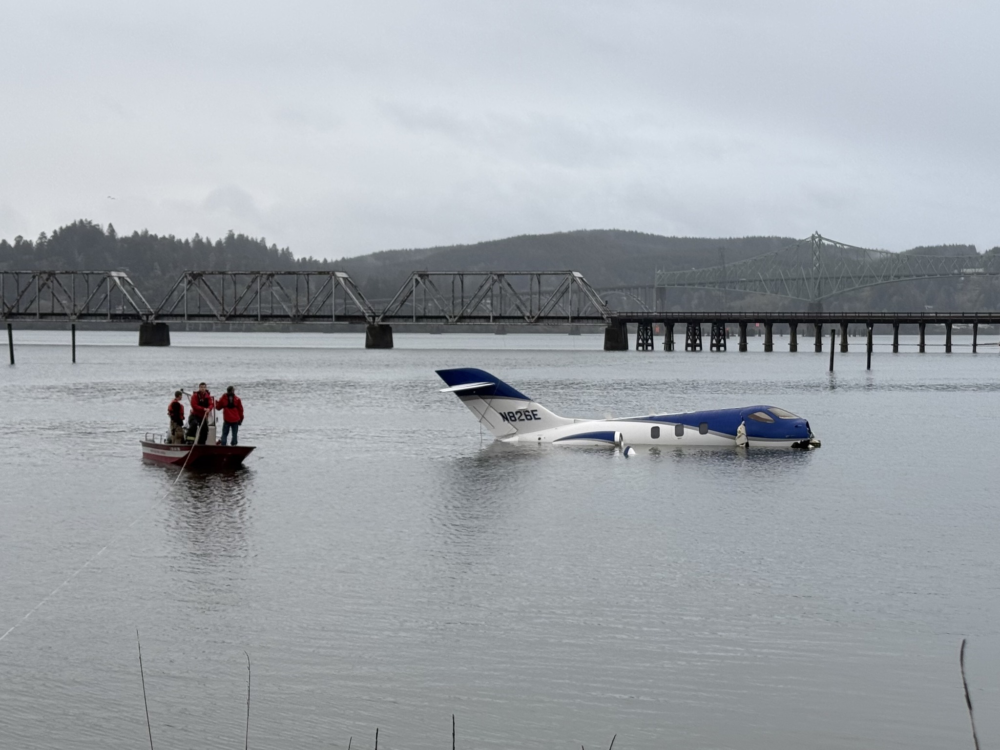 Crews salvage a private jet from the water near a Southwest Oregon Regional Airport runway on Monday. Airport officials said five people were rescued after the plane skidded off the runway.