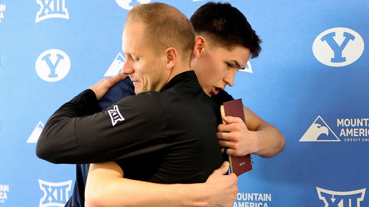 BYU head basketball coach Kevin Young hugs BYU point guard Egor Demin during a press conference about Demin’s plans to enter the NBA draft at the Marriott Center Annex in Provo on Tuesday, April 8, 2025.