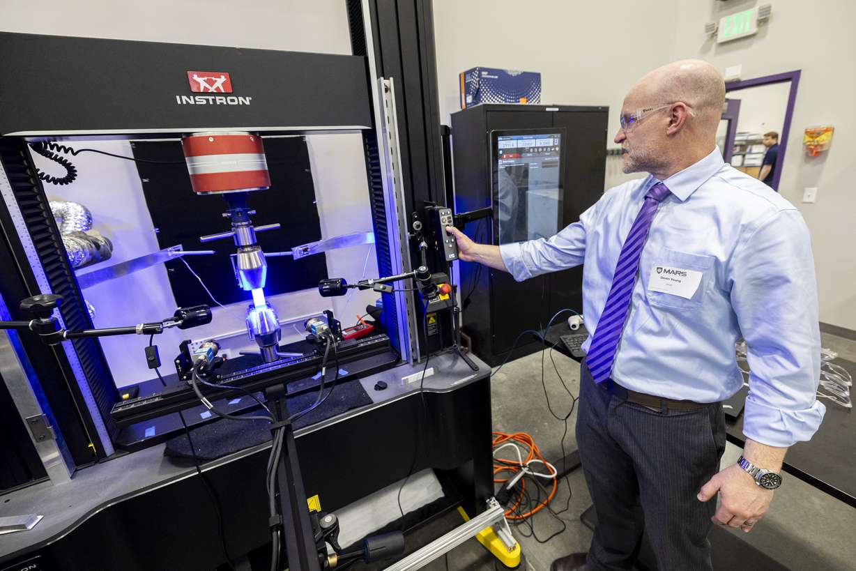 Devin Young, a research scientist with MARS, explains the uses of a universal testing system or load frame as it tests the range of strain of a piece of steel during an open house hosted by Weber State University and 47G held at the Miller Advanced Research & Solutions (MARS) Center near Hill Air Force Base in Clearfield on April 3.