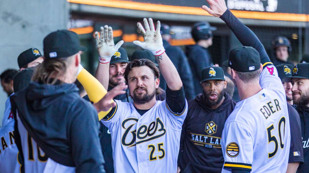 Salt Lake Bees crowd around infielder J.D. Davis to celebrate his grand slam in the first inning of the Bees' home opener at The Ballpark at America First Square in South Jordan on Tuesday.