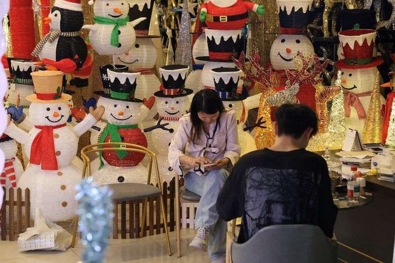 Workers at a Christmas decoration store use their phones at Yiwu International Trade Market, in Yiwu, Zhejiang province, China, Wednesday.