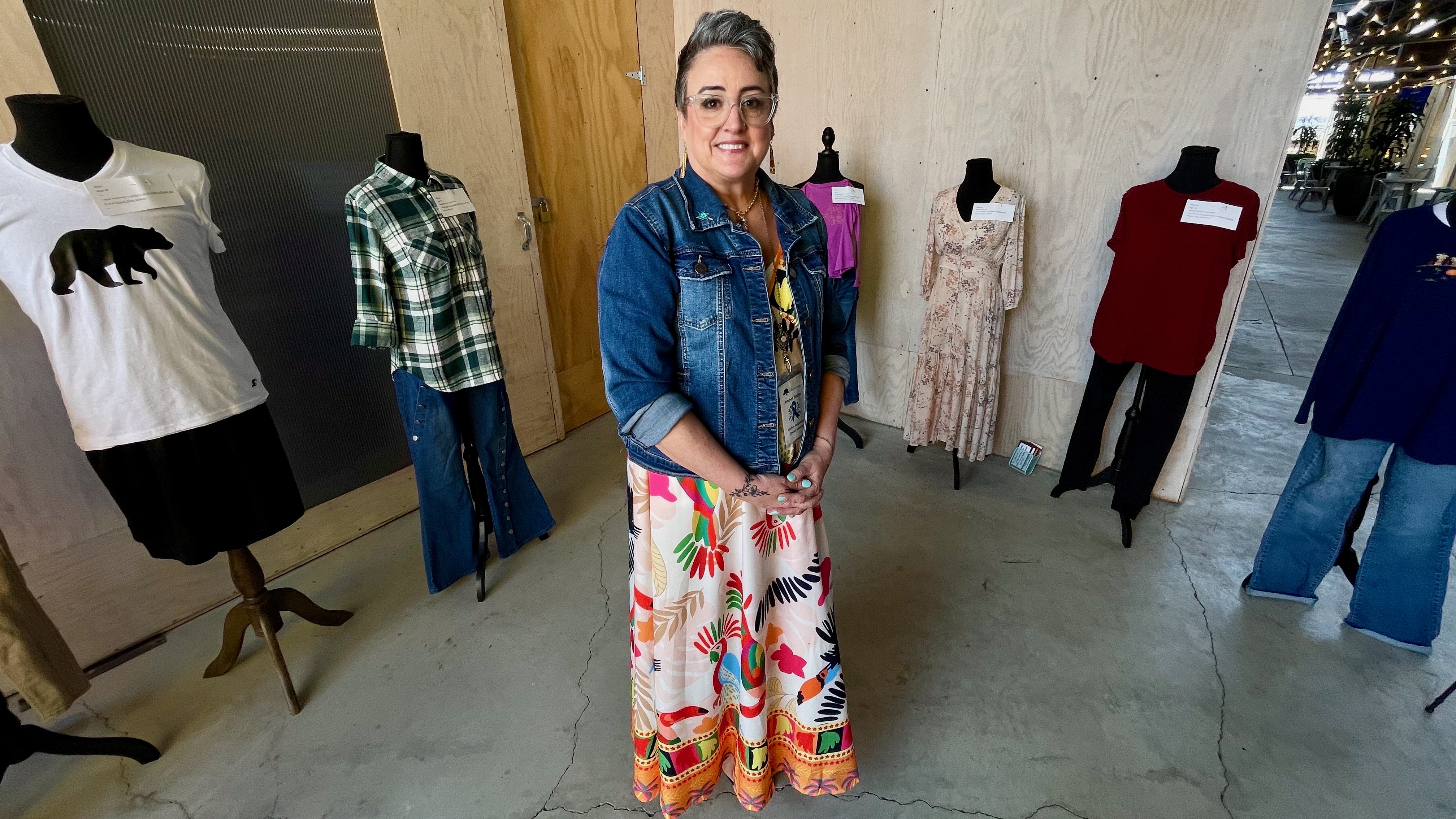 Amber Paaso, the victim assistance center director at YCC Family Crisis Center, stands in front of a "What were you wearing?" exhibit at the Monarch in Ogden on Thursday.