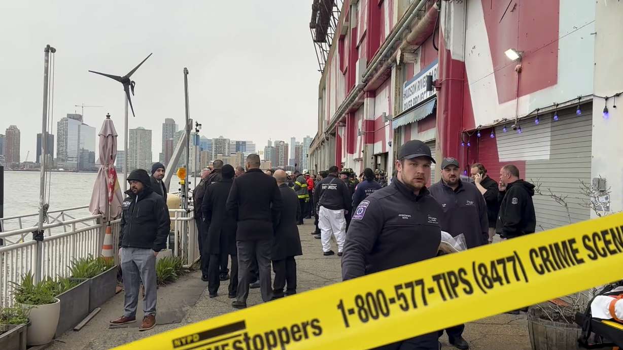 First responders walk along Pier 40, Thursday, in New York, across from where a helicopter went down in the Hudson River in Jersey City, N.J.
