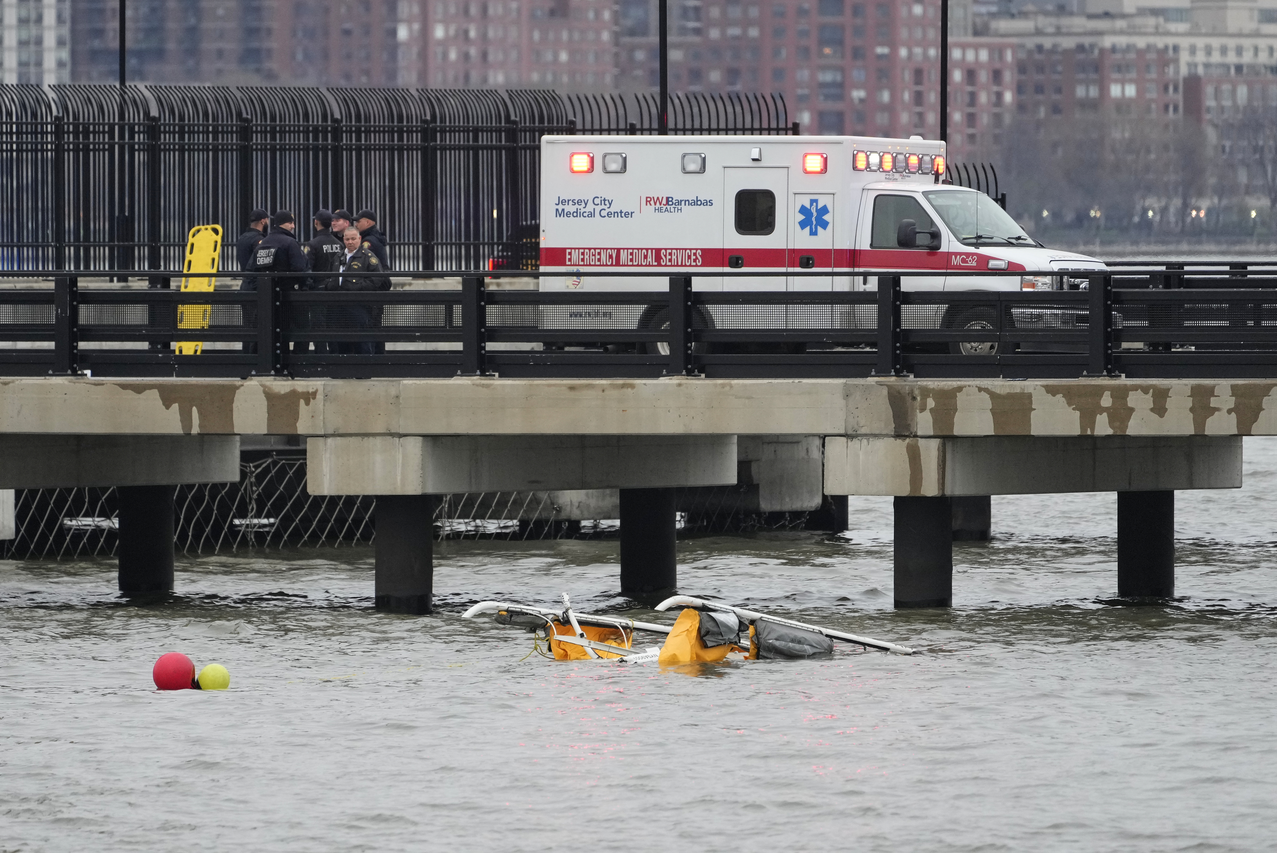 First responders stand on a pier at the scene where a helicopter crashed into the Hudson River Thursday in Jersey City, N.J.