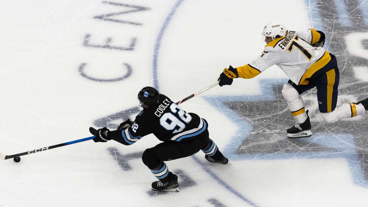 Utah Hockey Club center Logan Cooley (92) moves the puck down the ice against Nashville Predators right wing Luke Evangelista (77) during an NHL game at the Delta Center in Salt Lake City on Thursday, April 10, 2025.