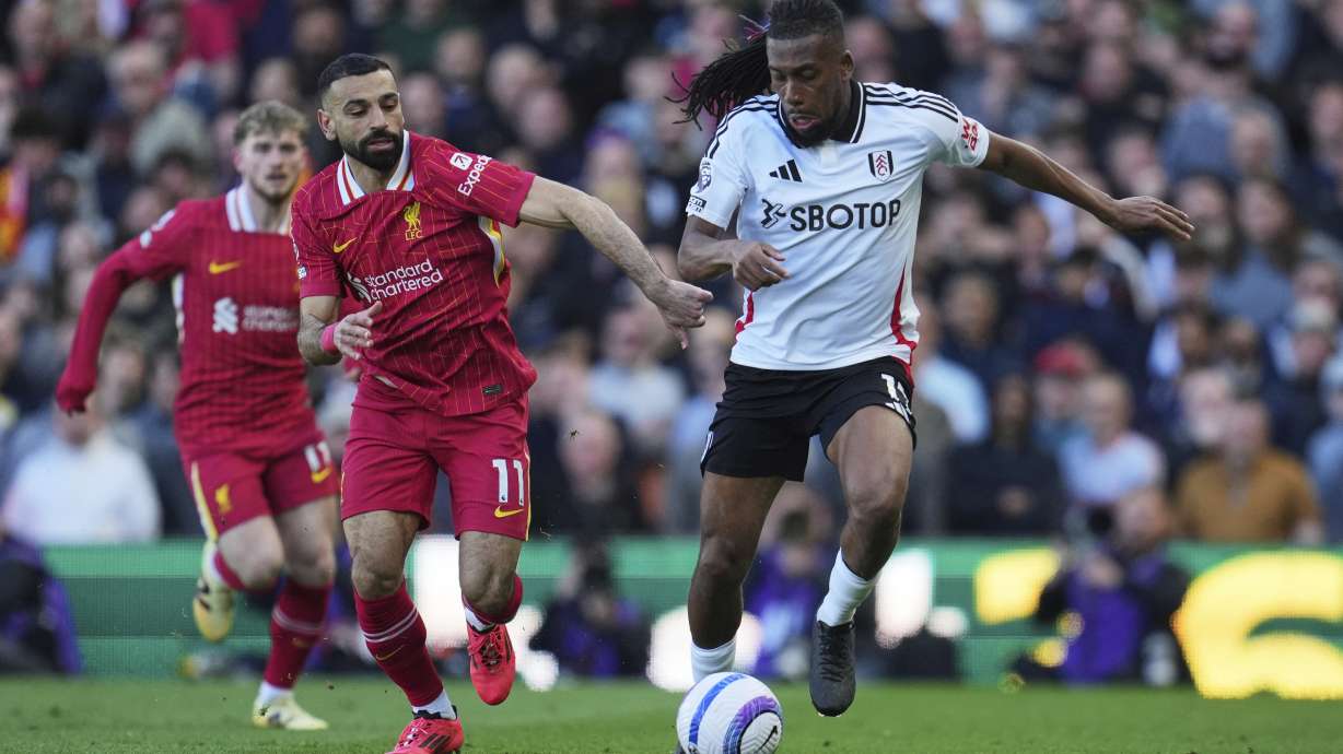 Fulham's Alex Iwobi, right, challenges for the ball with Liverpool's Mohamed Salah during the English Premier League soccer match between Fulham and Liverpool, at Craven Cottage, London, Sunday, April 6, 2025.