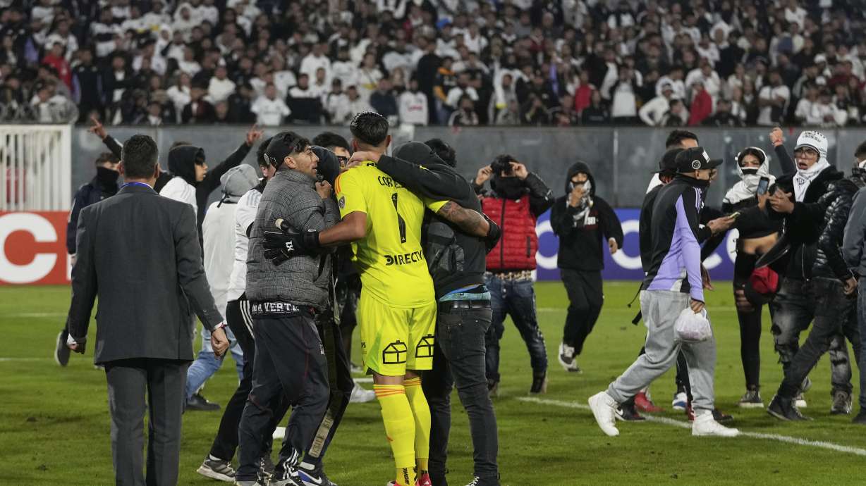 Goalkeeper Brayan Cortes of Chile's Colo Colo confronts fans who invaded the field during a Copa Libertadores Group E soccer match against Brazil's Fortaleza at the Monumental stadium in Santiago, Chile, Thursday, April 10, 2025.