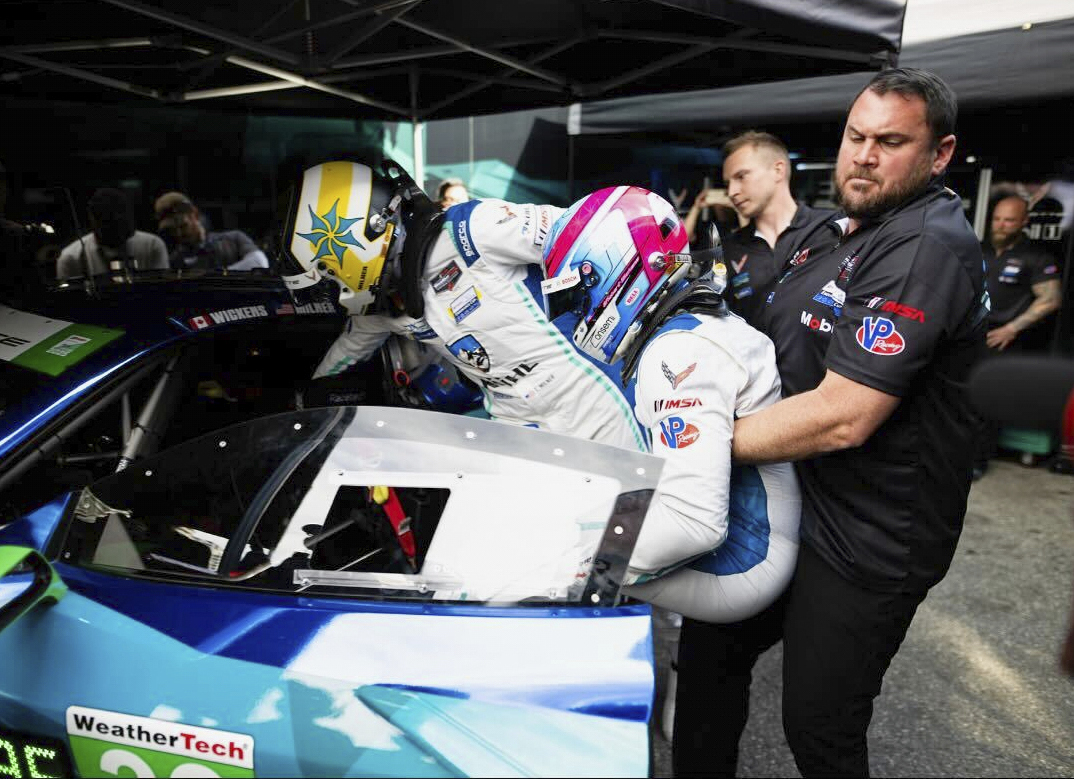Driver Change assist Josh Gibbs pulls Robert Wickens, who was paralyzed from the chest down after a 2018 IndyCar crash, from the car as Tommy Milner gets in the Chevrolet Corvette Z06 GT3R as they practice driving changes, Friday, April 11, 2025, in Long Beach Calif., for Saturday's IMSA auto race.