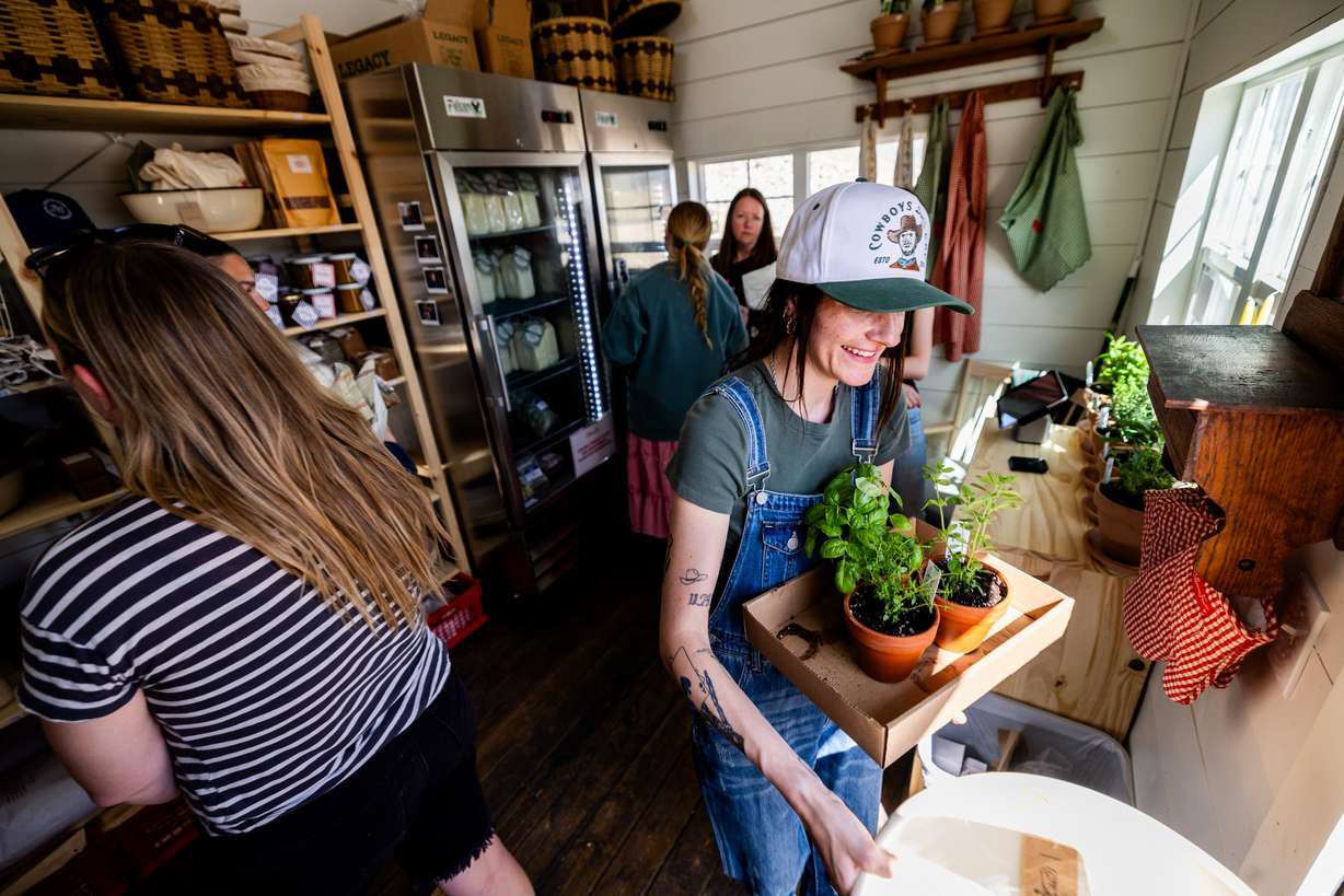 Employee Lilly Fryer carries herbs for a customer at Ballerina Farm’s new farm stand in Kamas on Thursday, April 11.