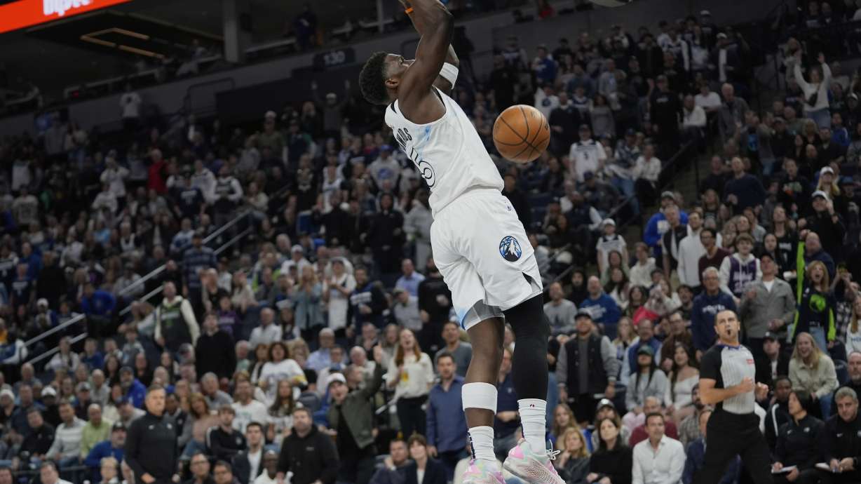 Minnesota Timberwolves guard Anthony Edwards hangs from the rim after making a basket during the first half of an NBA basketball game against the Brooklyn Nets, Friday, April 11, 2025, in Minneapolis.