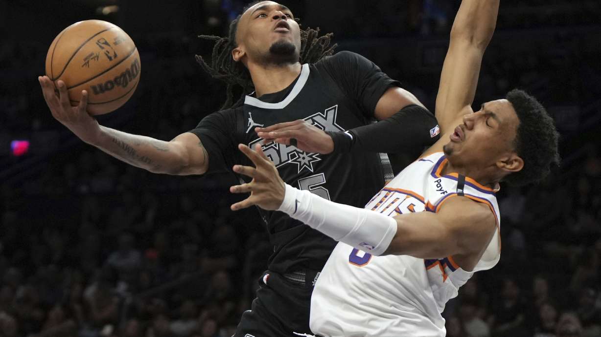 San Antonio Spurs guard Stephon Castle (5) drives on Phoenix Suns forward Ryan Dunn during the second half of an NBA basketball game, Friday, April 11, 2025, in Phoenix.