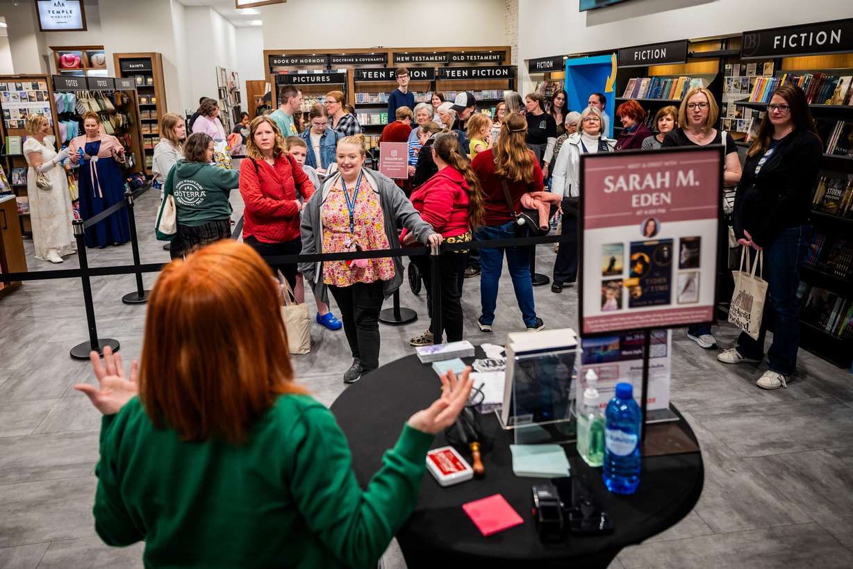 Author Sarah Eden motions for the first group in line to come to her table to have their books signed at a Deseret Book event at the City Creek Center in Salt Lake City on April 4.