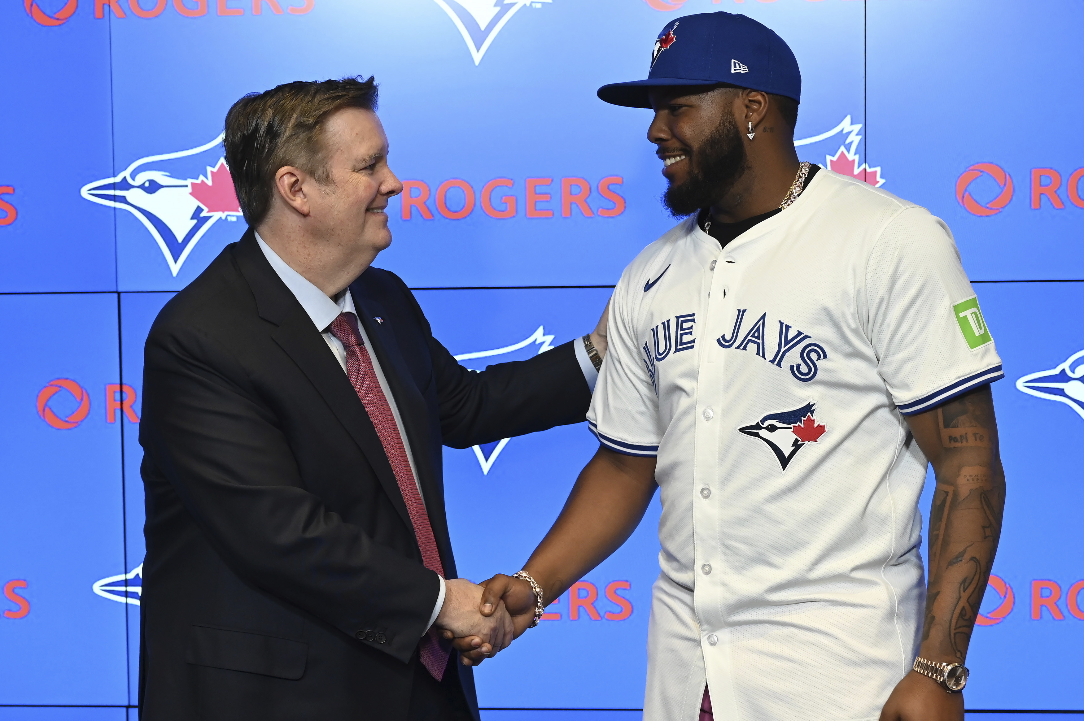 Edward S. Rogers III, chairman of the board of directors of Rogers Communications, left, shakes hands with Toronto Blue Jays first baseman Vladimir Guerrero Jr. at a press conference announcing Guerrero's 14 year, $500 million dollar contract extension in Toronto on Monday April 14, 2025.
