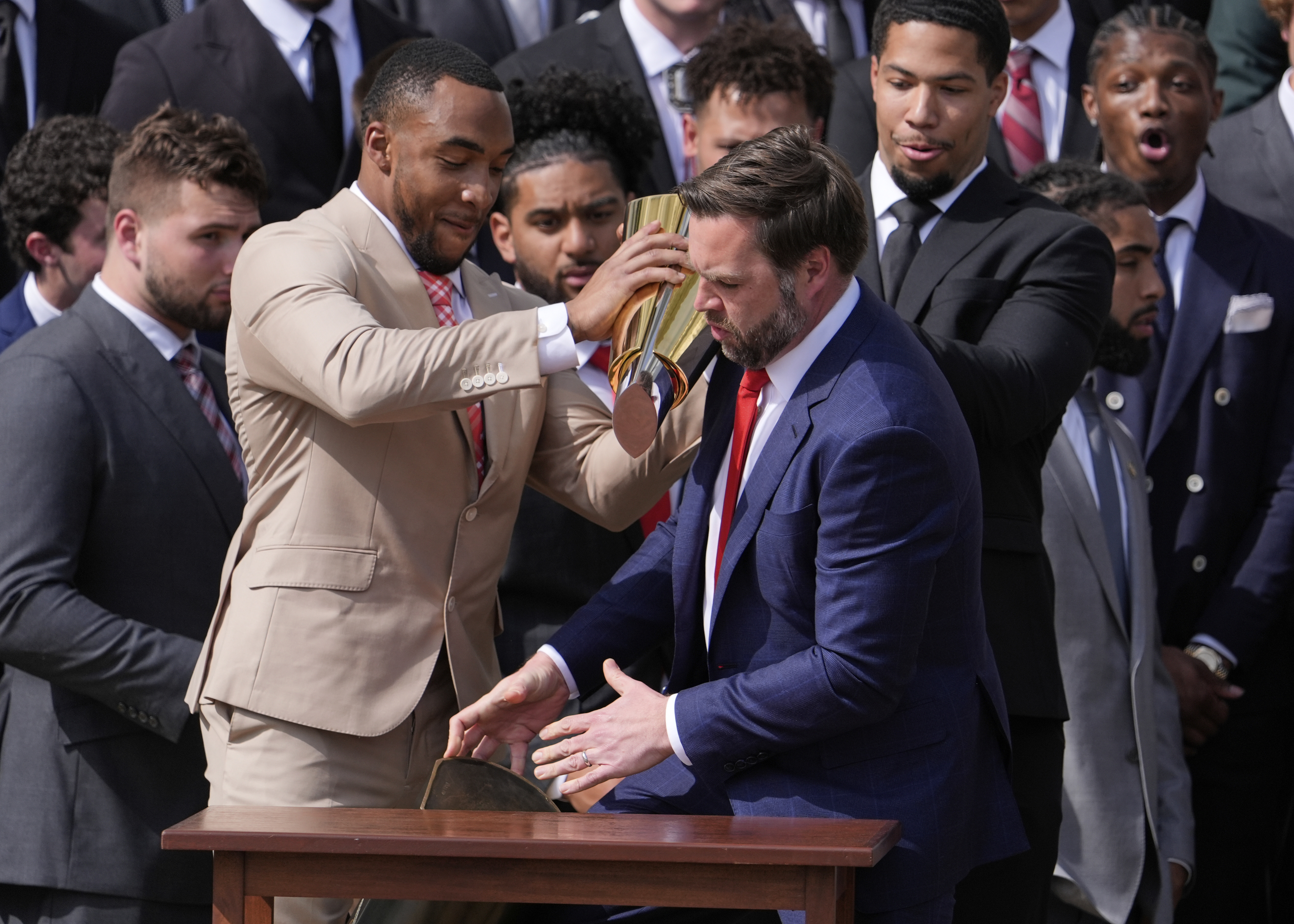 Ohio State University football player TreVeyon Henderson, left, holds the top of the team's championship trophy as Vice President JD Vance reaches to catch it's base after it fell off, as President Donald Trump welcomes the 2025 College Football National Champions during an event on the South Lawn of the White House, Monday, April 14, 2025, in Washington.