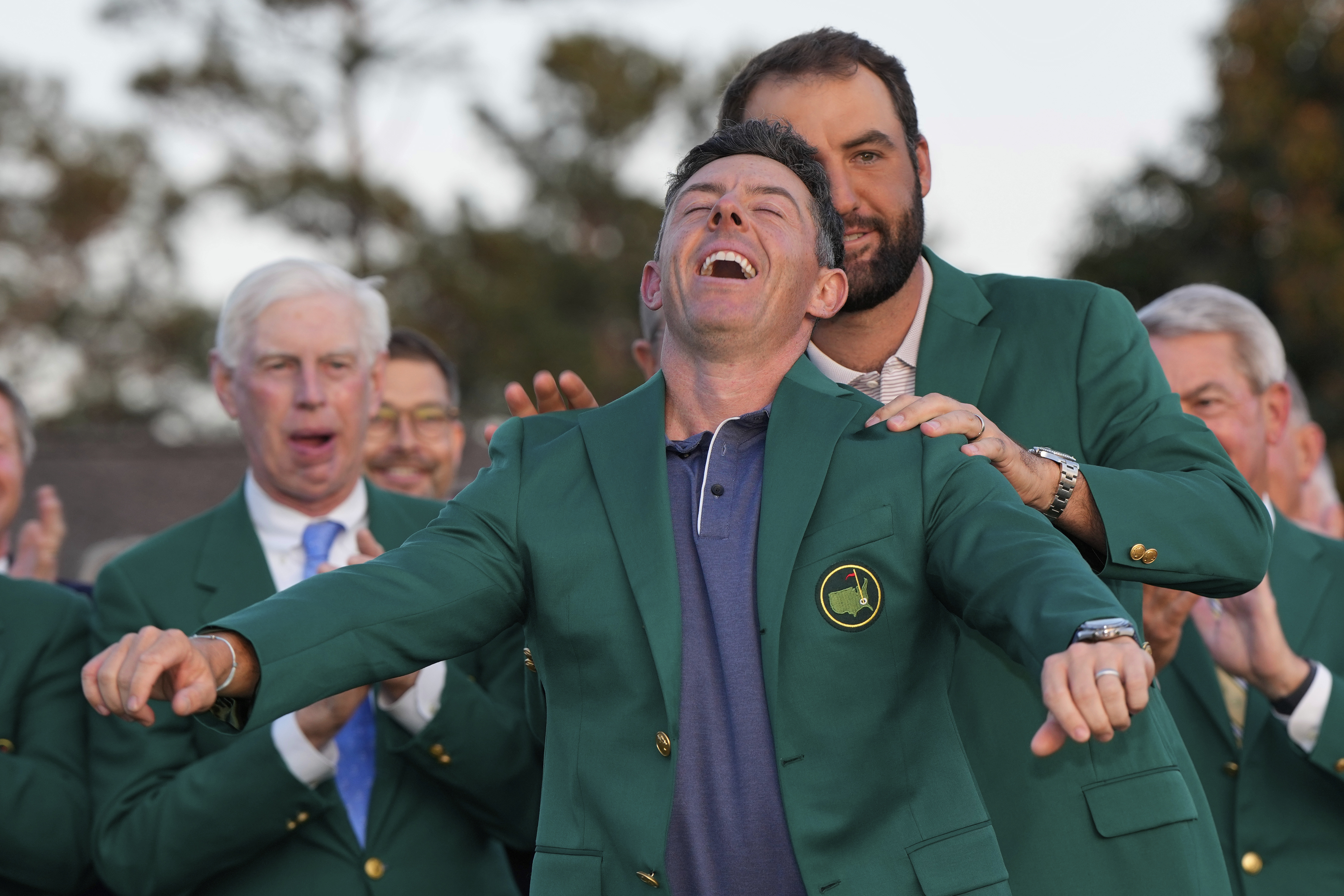 Scottie Scheffler puts the green Jacket on winner, Rory McIlroy, of Northern Ireland, at the Masters golf tournament, Sunday, April 13, 2025, in Augusta, Ga.