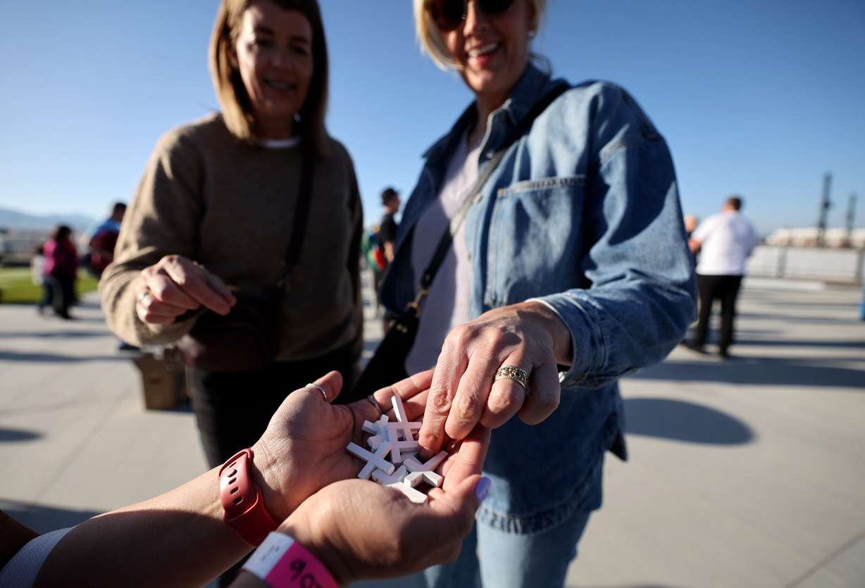 Women grab crosses at the Why I Believe Interfaith Easter Celebration at the Ballpark at America First Square in South Jordan on Monday.