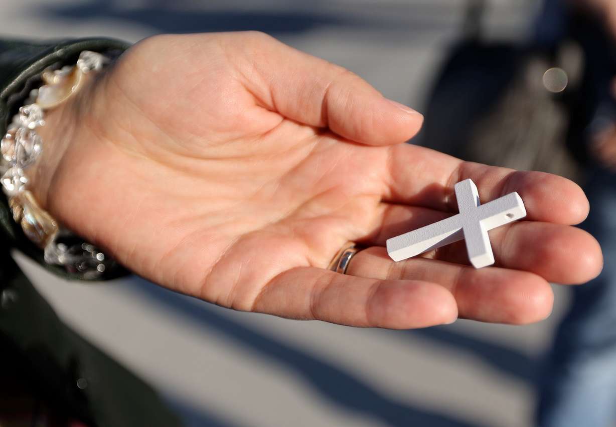 A woman holds a cross at the Why I Believe Interfaith Easter Celebration at the Ballpark at America First Square in South Jordan on Monday.