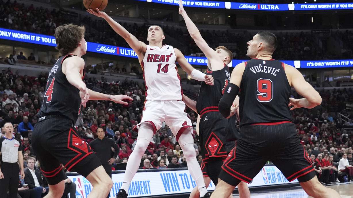 Miami Heat guard Tyler Herro (14) drives to the basket against Chicago Bulls forward Matas Buzelis, left, guard Kevin Huerter and center Nikola Vucevic, right, during the first half of an NBA play-in tournament basketball game in Chicago, Wednesday, April 16, 2025.